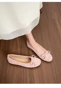 Detailopname van roze ballerina's met een fijne strik op een houten vloer