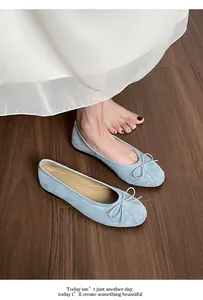 Gros plan sur des ballerines en daim bleu clair avec nœud délicat sur sol en bois