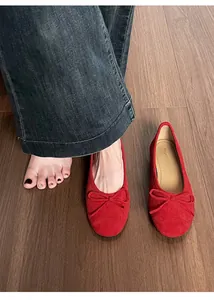 Gedetailleerd bovenaanzicht van rode zachte ballerina's met strik op houten vloer