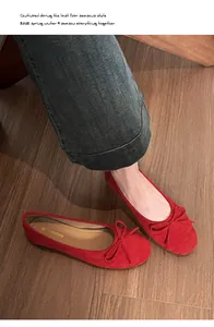 Bovenaanzicht van rode suède ballerina's met strik op een natuurlijke houten vloer achtergrond