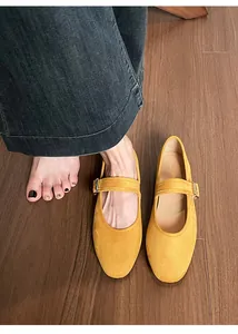 Détail de ballerines Mary Jane en daim jaune avec boucle sur parquet en bois