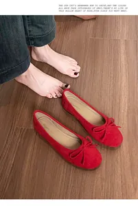 Detailopname van rode suède ballerina's met strik op een stijlvolle houten vloer