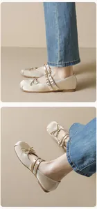 Detail of champagne satin ballet flats featuring delicate bows and metal eyelet straps
