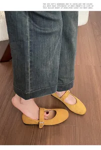 Gros plan de ballerines Mary Jane en daim jaune avec bride et pantalon en jean gris