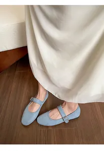 Gros plan sur des babies Mary Jane en daim bleu clair avec surpiqûres et boucle argent