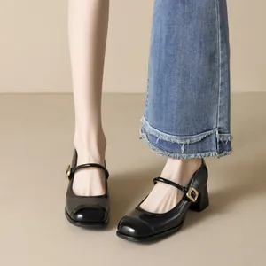Classic black patent leather square toe Mary Jane heels with gold buckle on model