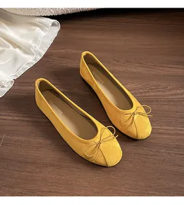 Détail de ballerines en daim jaune moutarde avec nœud sur un sol en bois vintage
