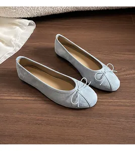 Détail de ballerines plates en daim bleu clair avec nœud délicat et bout rond élégant