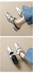 Detailansicht silberner Metallic-Mules mit Schleife und schwarzem Blockabsatz