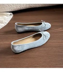 Vue détaillée de ballerines en daim bleu clair avec nœud sur fond en bois naturel