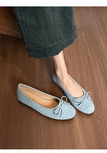 Detailopname van lichtblauwe suède ballerina's met strik en nauwkeurig stiksel op de wreef