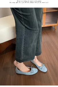 Detail van lichtblauwe suède ballerina's met strikje gedragen met grijze jeans