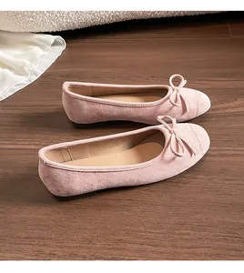 Detailweergave van roze suède ballerina's met strik op een warme houten vloer
