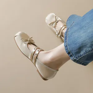Champagne satin ballet flats with bow and double straps on model in blue jeans