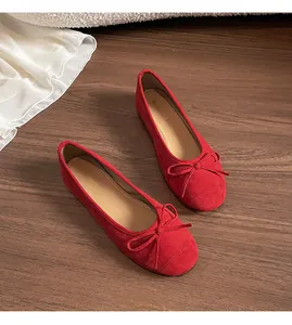 Detailopname van rode suède ballerina's met een fijne strik op een houten ondergrond