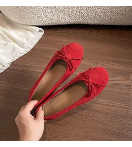 Detail van rode suède ballerina's met delicate strik op een gladde houten vloer achtergrond