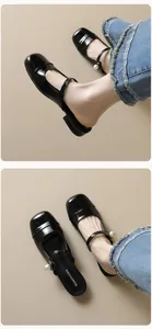 Close-up of black patent leather mules with white pearl strap and vintage square toe