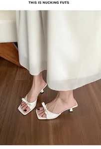 Vista superior de elegantes mulas blancas de tacón bajo con detalle de lazo