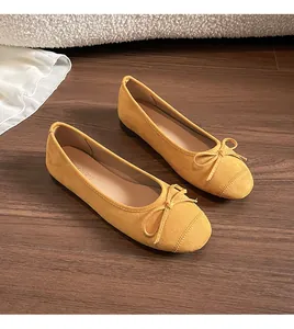 Bovenaanzicht van gele suède ballerina's met strikje op een donkere houten vloer