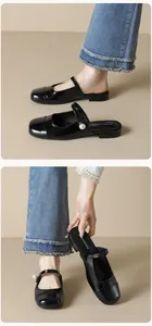 Macro detail of black patent leather Mary Jane mules featuring a large pearl embellishment