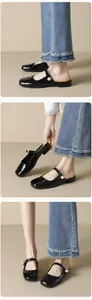 Detail of black patent leather mules with pearl strap buckle and glossy finish