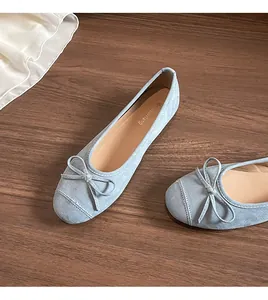 Detailopname van lichtblauwe suède ballerina's met strikje op een houten vloer