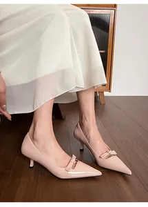 Détail d'escarpins pointus rose clair à petit talon et nœud portés avec une robe