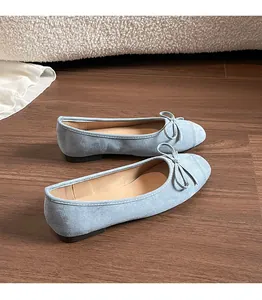 Detail van lichtblauwe suède ballerina's met sierlijke strik op houten vloer