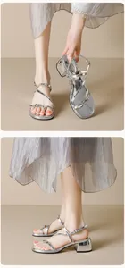 Close-up of silver strappy sandals with square metal buckles and a low block heel