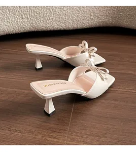 Detalle de elegantes sandalias crema con lazo, punta cuadrada y tacón fino
