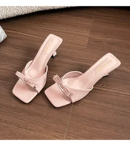 Detalle de sandalias mules rosas con lazo decorativo y elegante tacón fino