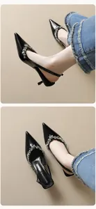 Macro detail of pointed-toe black patent leather slingback heels with crystal ornaments