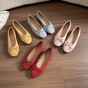 Platte ballerina's in geel, blauw, roze en rood met strik op houten vloer
