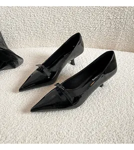 Détail de chaussures à bout pointu en cuir verni noir avec un nœud élégant