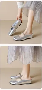 Detail of silver round toe Mary Jane mules featuring metallic strap and textured finish