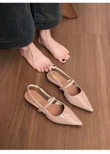 Dettaglio di ballerine slingback in vernice nude a punta su un pavimento in legno