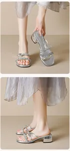 Close-up of silver glitter sandals with rhinestone bows and mirror-finish block heels