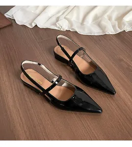 Dettaglio di scarpe basse a punta in vernice nera con eleganti cinturini doppi e fibbie