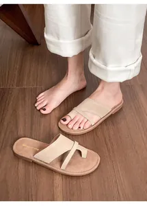 Detail view of beige leather thong sandals on model featuring minimalist cross-strap design