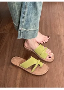 Close-up of green leather toe-loop flat sandals with white stitching detail