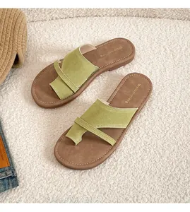 Detail of green suede thong sandals with cross straps and white stitching on brown soles