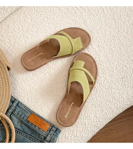 Close-up of light green suede thong sandals with brown leather footbed and fine stitching