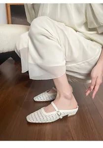Close-up of cream woven hollow-out pointed-toe mules with elegant metal buckle strap