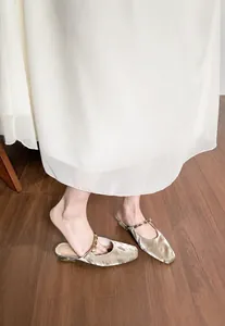 Elegant champagne gold pointed toe mules with jeweled strap on a model feet