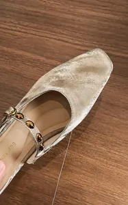 Detail display of champagne gold microfiber leather mule with metallic finish and rivets