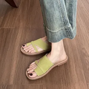 Grass green suede flat slide sandals for women with cross straps on wooden floor