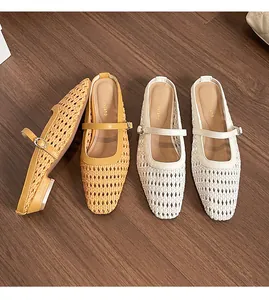 Overhead view of woven hollow pointed-toe mules in yellow and white on wooden floor