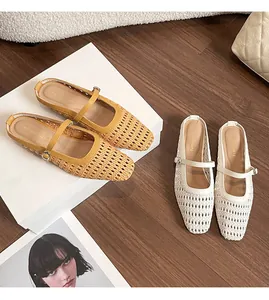 Detail of woven cutout Mary Jane slippers in yellow and white on a wooden floor
