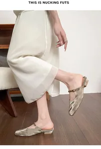 Macro view of gold metallic square-toe mule flats with decorative bead-embellished strap