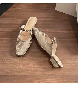 Detail view of silver square toe mule with metallic finish and gold rivet strap